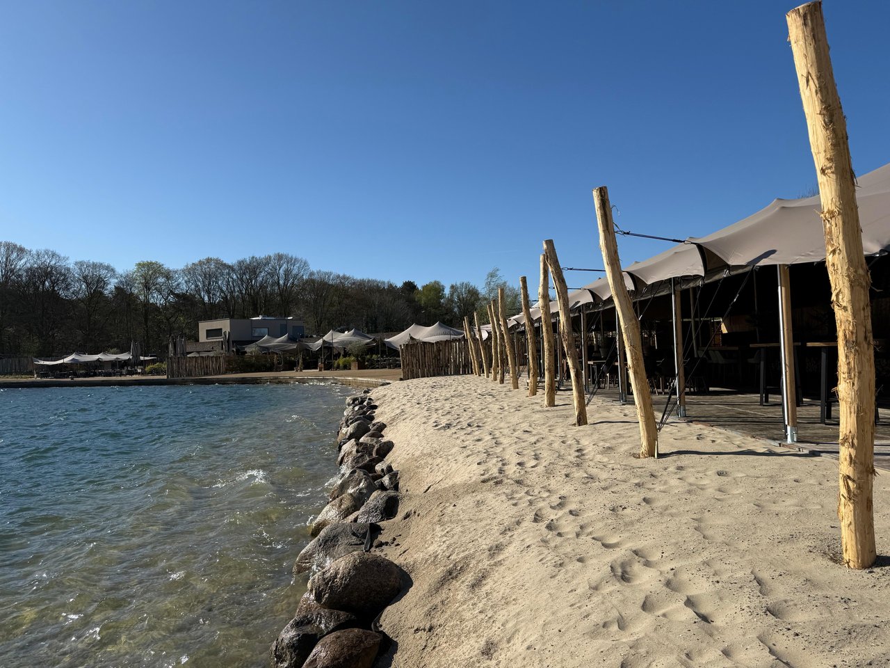 Zandstrand met stretchtent aan het water
