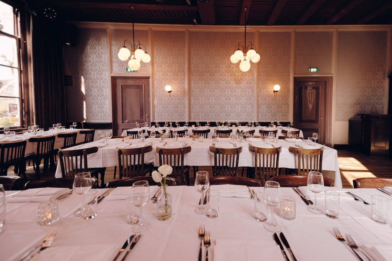 Feestelijk gedekte lange tafels voor een bruiloftsdiner in de Grote Zaal van Het Broeker Huis