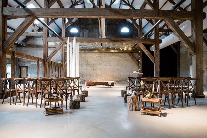 Huwelijks ceremonie in landelijke setting. Mooie, rustige houtlook, witte draperie doeken over de balken, boomstambankje.